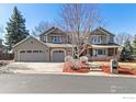 Beautiful home with a three-car garage, stone accents, and mature landscaping at 644 S Manorwood Ln, Louisville, CO 80027