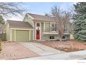 Inviting home with a red door, manicured landscaping, and an attached garage at 138 S Washington Ave, Louisville, CO 80027