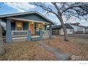 A charming blue single-story home with a welcoming front porch and a walkway leading to the entrance at 1560 Clinton St, Aurora, CO 80010