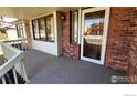 Inviting covered front porch with brick detailing and neutral-toned carpet at 2136 Westlake Dr, Longmont, CO 80503