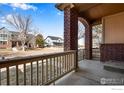 Covered porch with brick columns, railing and neighborhood view at 2443 Winding Dr, Longmont, CO 80504