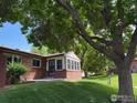 Charming brick home with a welcoming sunroom and mature trees shading the front yard at 2604 Elmhurst Cir, Longmont, CO 80503