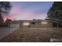 Ranch-style home at dusk featuring brick facade, attached garage, and a well-maintained front yard at 3045 Mcintosh Dr, Longmont, CO 80503