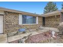 Inviting brick home featuring a cozy front porch, mature trees, and decorative landscaping elements at 3045 Mcintosh Dr, Longmont, CO 80503