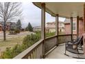 Relaxing covered porch with wicker chairs overlooking a serene neighborhood landscape at 366 Blackhawk Ln, Lafayette, CO 80026