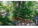 Wooden deck and railing overlooks a creek surrounded by lush vegetation creating a nature filled outdoor living space at 531 Arapahoe Ave, Boulder, CO 80302