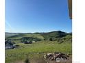 Scenic view of green hills and distant mountains from this home's backyard at 5489 Country Club Dr, Larkspur, CO 80118