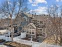 View of the townhome's blue siding and roof, complemented by bare winter trees and a white picket fence at 588 Beauprez Ave, Lafayette, CO 80026