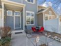 Welcoming front porch featuring a blue entrance door, red patio furniture, and a cozy outdoor sitting area at 588 Beauprez Ave, Lafayette, CO 80026