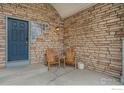 Inviting front porch with stone accents, wooden chairs, and a decorative glass block window at 6657 Drew Ranch Ln, Boulder, CO 80301