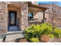 View of the front entryway, which features a stone archway and a decorative front door, and manicured bushes at 8426 Wilkerson Ct, Arvada, CO 80007