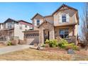 Two story home with a beige exterior, stone accents, two car garage, manicured lawn, and a concrete driveway at 8426 Wilkerson Ct, Arvada, CO 80007