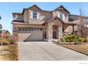 Two story home with a beige exterior, stone accents, two car garage, manicured lawn, and a concrete driveway at 8426 Wilkerson Ct, Arvada, CO 80007