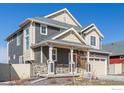 Angle view of charming two-story home featuring a covered porch, neutral siding, and a two-car garage at 1079 Larkspur Dr, Erie, CO 80516