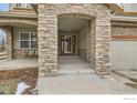 Covered front porch featuring stone columns and an inviting entryway with a bench at 14180 Whitney Cir, Broomfield, CO 80023