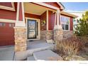 Inviting front porch featuring stone accents, decorative wreath, and a welcoming entrance at 1038 Petras St, Erie, CO 80516