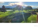 Picturesque view of the golf course with a pond, lush greenery, and mature trees at 1143 Purdue Dr, Longmont, CO 80503