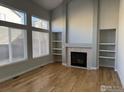 Bright living room with a fireplace, built-in shelves, large windows, and sleek hardwood floors at 1406 Vinca Pl, Superior, CO 80027