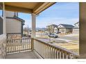 Inviting covered porch with railing offers neighborhood views and mountain backdrop at 316 Taurus Dr, Erie, CO 80516