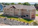 Expansive backyard with stone features, a lush lawn, and outdoor seating area on a multi-tiered patio at 3916 Fowler Ln, Longmont, CO 80503