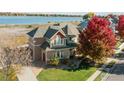 Two-story home featuring a well-manicured lawn, mature trees, and inviting curb appeal with lake in background at 3916 Fowler Ln, Longmont, CO 80503