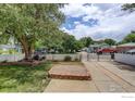 Exterior view of landscaped front yard with mature trees and gated driveway at 724 Carbon St, Erie, CO 80516
