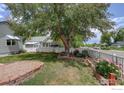 Exterior view of landscaped front yard featuring mature trees and flower garden at 724 Carbon St, Erie, CO 80516