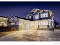 Charming two-story home exhibiting manicured lawn, covered porch, and attached garage at night at 785 Delechant Dr, Erie, CO 80516