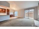 Inviting living area featuring sliding glass doors to a fenced patio, neutral paint, and stone fireplace at 8483 Everett Way # A, Arvada, CO 80005