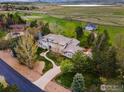 Wide aerial shot of a home nestled among mature trees, featuring a long driveway and manicured lawn at 8845 Crimson Clover Ln, Longmont, CO 80503