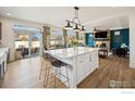 The kitchen island overlooks an open floorplan with dining area and living room with a statement fireplace at 1015 Auburn Dr, Erie, CO 80516