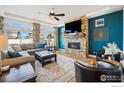 Bright living room featuring a brick fireplace, a ceiling fan, and an expansive window with neighborhood views at 1015 Auburn Dr, Erie, CO 80516