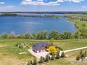 Expansive aerial view of the home, with a large lake as a backdrop and lush landscaping at 2366 Shoreside Dr, Berthoud, CO 80513