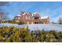 Brick house with snow-covered back lawn and shrubbery, offering a cozy winter scene at 2366 Shoreside Dr, Berthoud, CO 80513