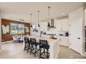 Modern kitchen seamlessly connects to the dining area, featuring a spacious island with bar seating and contemporary lighting fixtures at 2747 Crystal Springs, Longmont, CO 80503