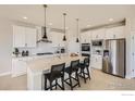 This kitchen features white cabinets, stainless steel appliances, a spacious island with seating, and modern pendant lighting at 2747 Crystal Springs, Longmont, CO 80503