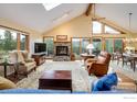 An inviting living room featuring a stone fireplace, vaulted ceilings, and abundant natural light with access to outdoor balcony at 302 Deer Trail Cir, Boulder, CO 80302