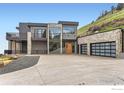 Sleek modern home with a stone facade, large windows, and a spacious driveway in a mountainside setting at 3645 Cholla Ct, Boulder, CO 80304
