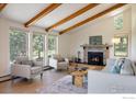 Comfortable living room featuring a cozy fireplace, wooden beams, and large windows with natural light at 67 S Peak Rd, Boulder, CO 80302