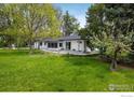 Well-maintained home exterior, complemented by a lush green lawn and mature trees at 10587 N 95Th St, Longmont, CO 80501