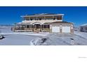 Exterior view of a two story home featuring a wraparound porch and an attached two-car garage in winter at 1255 Mill Creek Rd, Berthoud, CO 80513