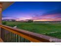 Scenic sunset view from the porch overlooking a lush green field and distant mountains at 1255 Mill Creek Rd, Berthoud, CO 80513