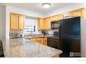Updated kitchen featuring wood cabinets, granite countertops, and black appliances at 1405 Broadway # 101, Boulder, CO 80302