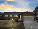 Well-maintained brick home with a two-car garage, mature landscaping, and a welcoming entryway, photographed at dusk at 161 Baylor Dr, Longmont, CO 80503