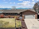 Charming single-story brick home featuring a two-car garage, well-kept lawn, and mountain views in the background at 161 Baylor Dr, Longmont, CO 80503