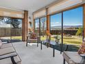 Relaxing sun room filled with natural light and comfortable seating showcasing views of the fenced yard and mountains beyond at 161 Baylor Dr, Longmont, CO 80503