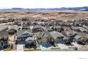 Wide aerial view of a residential neighborhood nestled among rolling hills and mountains in the distance on a sunny day at 18740 W 85Th Dr, Arvada, CO 80007