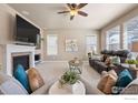 Cozy living room with a fireplace, plush seating, a ceiling fan, and large windows offering natural light at 18926 W 93Rd Ave, Arvada, CO 80007