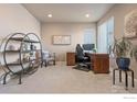 Inviting home office with neutral walls, plush carpeting, a wooden desk, and decorative shelving for a productive workspace at 18926 W 93Rd Ave, Arvada, CO 80007