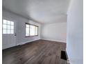 Bright living room featuring new wood floors, a window, and a white door at 2085 Carr St, Lakewood, CO 80214